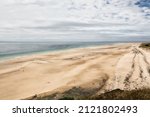 Scene of beach side with cloudy sky, desaturated colors. Golden hour dune sand grass ocean sea,majestic nature landscape. Beautiful beach in Cotentin Carteret Manche France. Mystic landscape