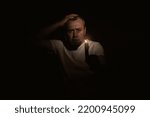 Small photo of Frightened man with a candle during blackout. Man looking at the camera with a candle in the dark. Blackout concept.