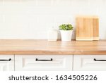 Bright And Clean Kitchen With White Cabinets, Close Up. Cutting Boards, Green Succulent Pot On A Wooden Worktop. Kitchenware In Modern Kitchen Interior. White Tiles Background