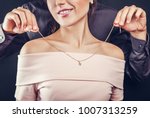 Man helping his girlfriend to try on a golden necklace on black background. Gift for Valentines day.