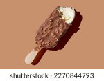 Bitten chocolate ice cream on a stick brown pastel background