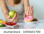 Dieting or good health concept. Young woman rejecting Junk food or unhealthy food such as donut or dessert and choosing healthy food such as fresh fruit or vegetable.