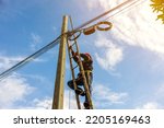 Small photo of A telecoms worker is shown working from a utility pole ladder while wearing high visibility personal safety clothing, PPE, and a hard hat.