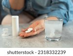 Female hands with pills on background of water glass with effervescent tablet. Soluble drug.Take medicine, vitamins.