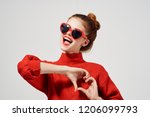 a woman in dark glasses and a red sweater folded her arms in the form of a heart                           