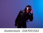 Small photo of Excited pretty awesome brunet woman in leather jacket touch trendy specular sunglasses open mouth posing isolated in blue violet color light background. Neon party Cyberpunk concept. Copy space