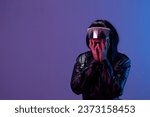 Small photo of Shocked pretty awesome brunet woman in leather jacket trendy specular sunglasses open mouth touch cheeks posing isolated in blue violet color light background. Neon party Cyberpunk concept. Copy space