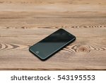 Black smartphone lying on a wooden table