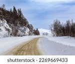 A frosty winter morning in a mountainous area, a snow-covered road is the only way out of snow captivity.
