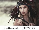 Small photo of beautiful girl with a feather in the hands. young woman in a homemade headdress Native Americans of feathers. roach, war bonnet. the concept of woman on the warpath