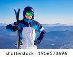 Happy skier man holding pair of skis background snowy mountains, concept sport active winter banner.