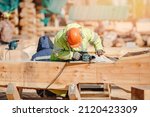Small photo of Industrial work carpenter grinds log with electric jointer, construction frame building site of house made of wood.