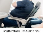 Fat obese man passenger fastening seat belt on airplane, problem safe flight.