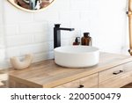 Small photo of Black faucet for water and white separate high sink on wooden pedestal. Loft style bathroom.