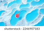 Travertine pools Pamukkale, Turkey travel. Woman swimming on pink inflatable donut in turquoise water, aerial top view.