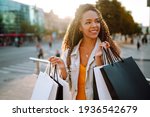 Small photo of Fashion woman with shopping bags walking on street. Spring Style. Consumerism, sale, purchases, shopping, lifestyle concept.