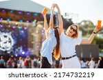 Small photo of Two young woman drinking beer and having fun at Beach party together. Happy girlfriends having fun at music festival. Summer holiday, vacation concept.