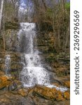 Small photo of A waterfall on the cliff side of Big Soddy Creek Gulf Trail in Tennessee cascades over the rocks and spills onto the trail. Most of the water is diverted under the trail and into the creek.