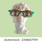 Small photo of White plaster statue head of David with big eyes and glasses green background.