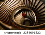 a girl in a red dress climbs a large spiral spiral staircase