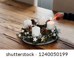 Close up of lighting the first candle on Advent Wreath on the first Sunday in December. Celebrating Christmas holidays, swiss tradition. Crop hand holding the safety matches to light the candle.