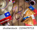 Small photo of Chilean independence day concept. fiestas patrias. Tipical baked empanadas, wine or chicha, fat and play emboque. Decoration for 18 september party day, wooden background, top view.