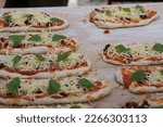 Small photo of occupied mini pizzas waiting to be baked thereon
