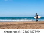 Small photo of A surfer walks towards the ocean to go surfing with his board. Sopelana beach near Bilbao. Day of relaxation, tranquility with little wind and incredible colors. Raider getting ready to play sports.