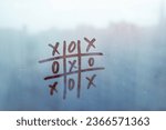 Small photo of Hand drawn tic-tac-toe game on foggy glass on blue window