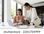 Small photo of Young businesswoman adviser standing in front of laptop and giving advise to sales woman. Business people consulting at office.