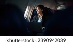 Small photo of Successful Asian business woman, Business woman working in airplane cabin during flight on laptop computer listening to music with headphones