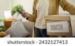 Small photo of Donation concept. Woman asian holding a donate box with full of clothes. Woman holding clothes donate box. Clothes in box for concept donation and reuse recycle