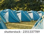 A tranquil summer retreat: A sprawling tent camp nestled in the heart of a lush forest, waiting for its occupants to return from their outdoor adventures.