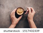 Female hands holding spoon and stirring hot coffee on a dark brown rustic background. Top view, flat lay