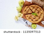 Homemade sliced apple pie on the wooden board decorated with fresh green apples, sugar cubes, mint leaves. Vegetarian tart on the white background. Delicious autumn dessert. Top view with copy space
