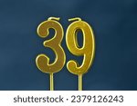 Small photo of close up on the gold number thirty-ninth candle on a dark background.