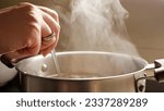 Small photo of Female hand stirring boiling soup in pot. Healthy nutrition, cooking at home, hot steam