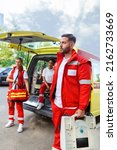 Small photo of Paramedic nurse and emergency doctor at ambulance with kit. a paramedic, standing at the rear of an ambulance, by the open doors.