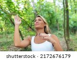 Small photo of Young woman outdoor wave her arms as she gets swarmed by pesky mosquitoes. Young tourist trying to get rid of annoying insects harassing her in the wild.