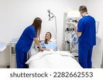 Hospital Ward: Friendly Doctor and nurse taking care of Beautiful Caucasian Female Patient Resting in Bed. Physician explains Test Results. Woman Recovering after Successful Surgery