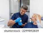 Small photo of Dentist showing dental plaster mold to the patient. Dentist doctor showing jaw model at dental clinic, dental care concept. Dental care concept.
