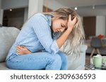 Small photo of Woman in painful expression holding hands against belly suffering menstrual period pain, lying sad on home bed, having tummy cramp in female health concept