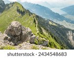 Summer view from Oberschildhorn mountain towards Schynige Platte in the Jungfrau region. Alpine mountains with hiking trail. Rocks in the foreground. Swiss Alps landscape. Thunersee in background.