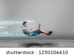 Fast levitating man in a white room using a laptop. High speed browsing.