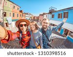 Happy friends making selfie photo in Burano island in Venice. Travel and vacation in Italy concept