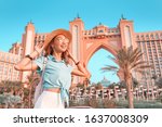 Happy indonesian girl traveler relaxing near famous luxury Atlantis hotel building on a Jumeirah Palm Island in Dubai, UAE