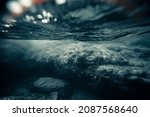 Small photo of A deserted and dark mystical underwater landscape with large rocks in shallow sea coast. Narrow depth and soft focus. Gloomy and moody atmosphere