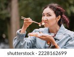 Small photo of A girl sniffs spoiled seafood in her sushi snacks. The concept of food poisoning and intoxication