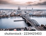 Small photo of Koln Aerial view with trains move on a bridge over the Rhine River on which cargo barges and passenger ships ply. The majestic Cologne Cathedral in the background