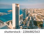 Small photo of A breathtaking view of Abu Dhabi's iconic skyscrapers rising majestically from the ground, their gleaming glass facades reflecting the bright blue sky above.